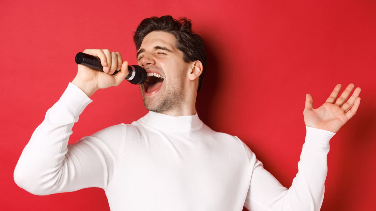 Joven adulto cantando con micrófono durante una clase de canto en Madrid, con entusiasmo y energía
