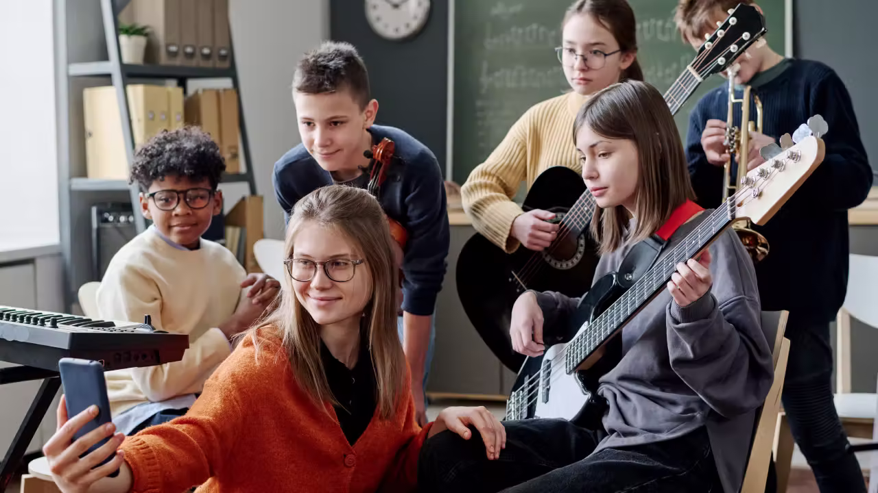 Grupo de adolescentes posando en una clase de música en Madrid, con instrumentos y partituras al fondo