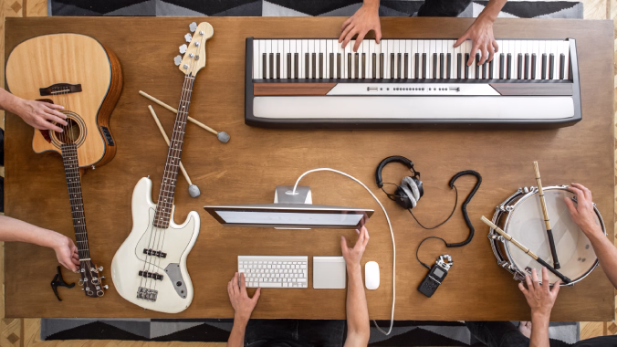 Diferentes instrumentos musicales como piano, guitarra y tambor, junto a un ordenador y manos tocando