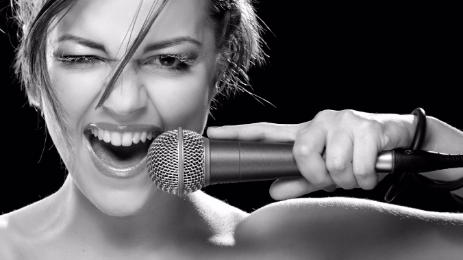 Alumna cantando con entusiasmo durante un ejercicio de técnica vocal en blanco y negro